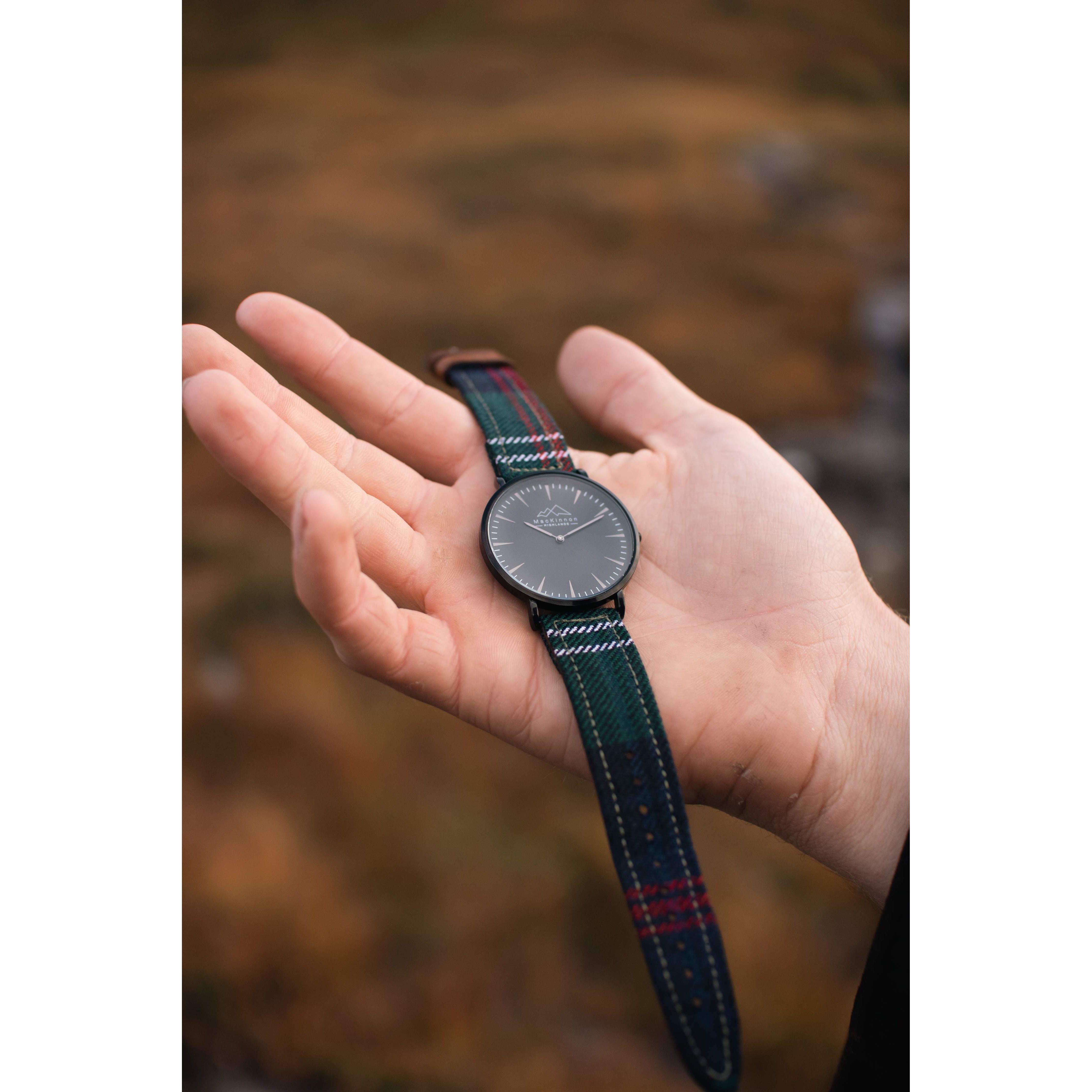 a hand holding a custom tartan watch with red blue green tartan