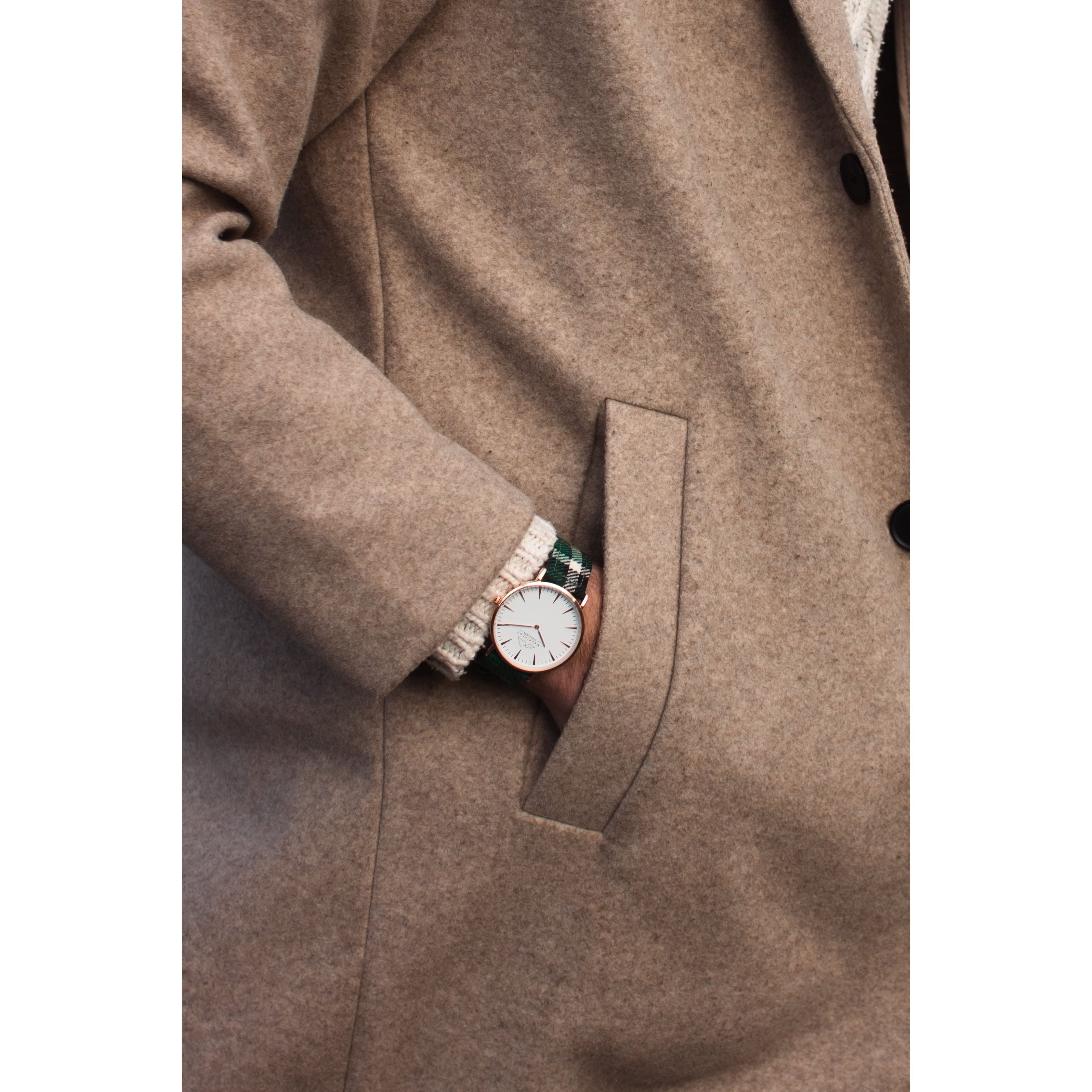 A man with a custom tartan watch with his hand in his jacket